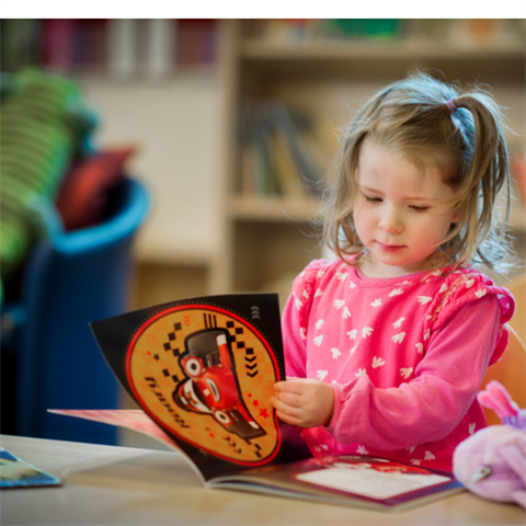 Child reading book in library