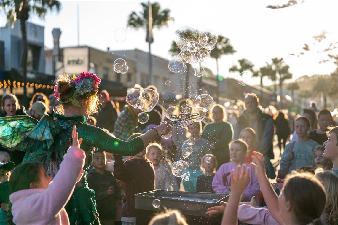 Street performer blowing bubbles into crowd of people