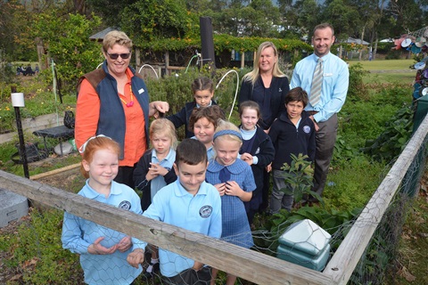 8 School children and three teachers standing in amongst raised garden beds